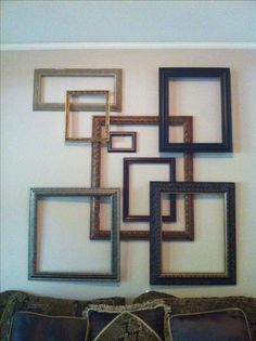 a living room filled with lots of framed pictures on the wall above a brown couch