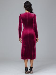 the back view of a woman wearing a long sleeved velvet dress with high slits