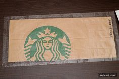 a starbucks bag sitting on top of a wooden table next to a pen and paper