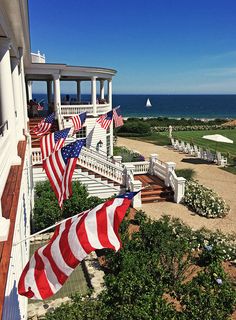 an american flag is flying on the front porch of a house overlooking the ocean and golf course