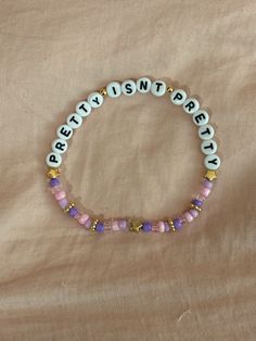 A hand-crafted glass bead friendship bracelet highlighting Olivia Rodrigo's song "Pretty Isn't Pretty"! A simple and cute way to show off your favorite song or a great concert accessory!  This bracelet is made with Czech glass beads, plastic letter beads, plastic spacer beads, and is on an elastic thread measured at about 10 inches in length for a relaxed/loose fit. If you would like the bracelet you order to be smaller or larger, please leave the requested size in inches in the personalization Adjustable Beaded Kpop Bracelets, Adjustable Round Beads Kpop Bracelets, Adjustable Kpop Style Friendship Bracelets With Letter Beads, Trendy Purple Beaded Bracelets For Festival, Trendy Beaded Name Bracelet For Friendship, Olivia Rodrigo Friendship Bracelet Ideas, Olivia Rodrigo Friendship Bracelet, Olivia Rodrigo Bracelets, Olivia Rodrigo Bracelet Ideas