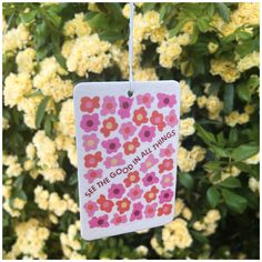 a tag that says get the good in all things hanging from a tree filled with yellow flowers