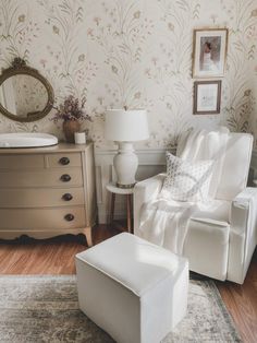 a white chair and ottoman in a room with floral wallpaper on the walls behind it