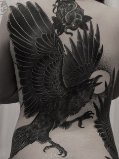 the back of a woman's body with a black bird tattoo on her lower back