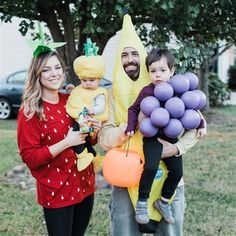 a family dressed up as bananas and balloons in the yard for halloween party with one child holding an orange balloon