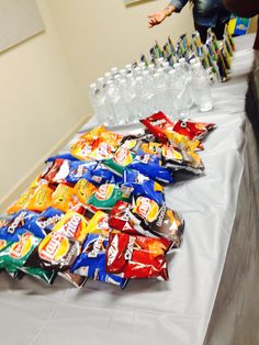 a table topped with lots of bags of chips and water bottles on top of it