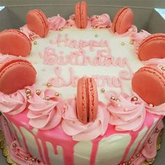 a birthday cake decorated with pink icing and cookies