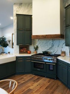 a large kitchen with green cabinets and marble counter tops on the walls, along with an oven