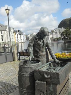 a statue of a man sitting on top of a wooden box next to a river