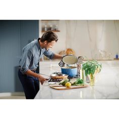 a man is cooking on the stove in his kitchen while looking down at something he's holding