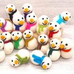 small snowmen with scarves and scarfs are arranged in a pile on a wooden surface