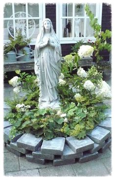 the statue is surrounded by white flowers and greenery