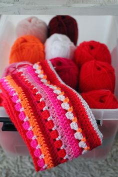 crocheted blankets and balls of yarn in a container