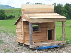 a small wooden house sitting on top of a gravel field next to a green field