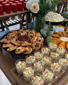 an assortment of food is displayed on a buffet table with cups and sauces in front of it