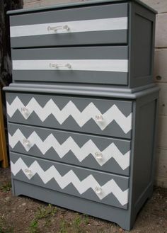 a gray and white dresser sitting on top of a grass covered field