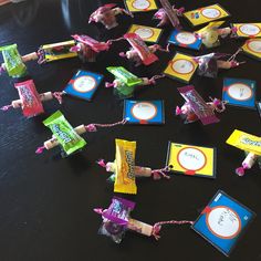 small candy bars tied to twine with pink and yellow tags on them, sitting on a table