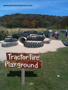 there is a sign that says tractor tire playground in front of some tires on the ground