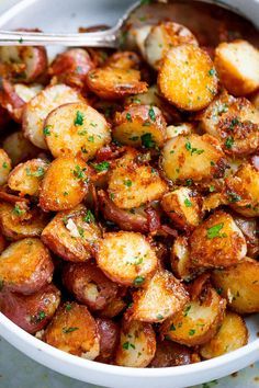 a white bowl filled with cooked potatoes on top of a table