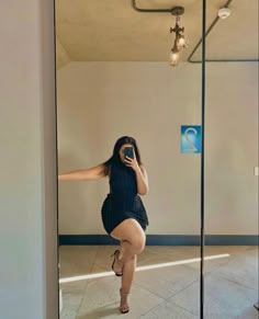 a woman taking a selfie in front of a mirror with her legs spread out