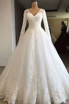 a white wedding dress with long sleeves and lace on the skirt is displayed in front of a