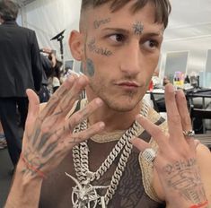 a man with many tattoos on his face and hands in front of him is making the peace sign