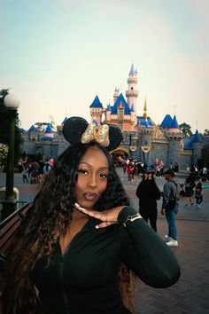 a woman poses for a photo in front of mickey mouse's castle at disneyland world