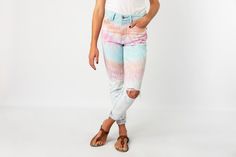 a woman in white shirt and tie dye jeans standing with her hands on her hips