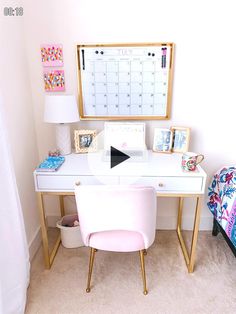 a white desk topped with a pink chair next to a wall mounted calendar and lamp