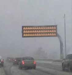 cars driving in heavy snow on a highway with an electronic sign showing the speed limit