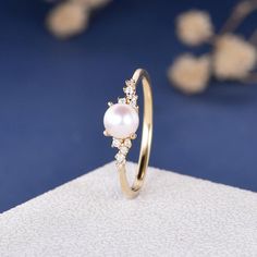 a pearl and diamond ring sitting on top of a table