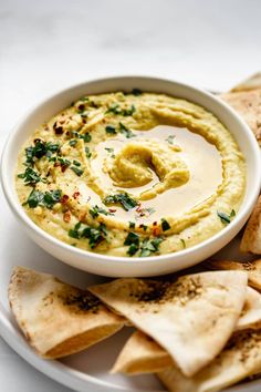 hummus and tortilla chips on a plate with dipping sauce in the middle