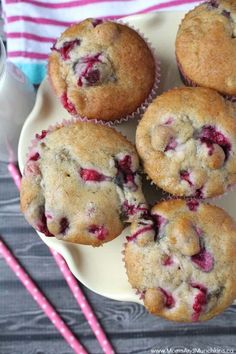 several muffins on a plate with strawberries and two pink striped drinking straws