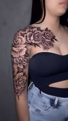 a woman with flowers on her arm and chest is posing for the camera while wearing jeans