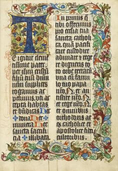 an illuminated book with floral designs and letters on the pages, including one letter t