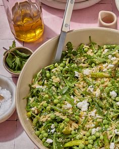 a large bowl filled with green vegetables on top of a table next to other dishes