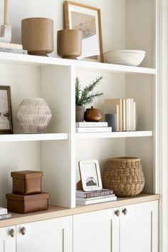 a white book shelf filled with books and vases