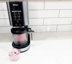 a black and silver coffee maker sitting on top of a counter next to a bowl of ice cream