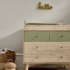 a wooden dresser sitting next to a wall with a hello sign on it's side