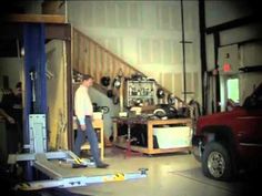 a man standing in a garage next to a red truck