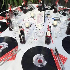 a table set up for a party with vinyl records and wine glasses on it, surrounded by red polka dot napkins