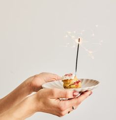 a person holding a plate with food and a sparkler in it's hand