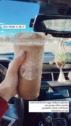 someone holding up a cup of coffee in their car