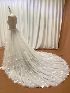 a white wedding dress on display in front of curtains