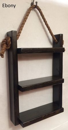 a wooden shelf with rope hanging from it's sides and two shelves attached to the wall