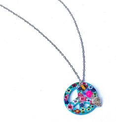 "A Boho necklace featuring a turquoise blue peace sign pendant that's covered in colorful painted flowers in pink, yellow, and purple, with sparkling Swarovski crystal rhinestone accents! Dangling alongside the artful pendant, a little silver heart charm and glass lampwork beads add fun movement! Just choose your chain length to add this super-cute piece of Boho-style wearable art to your collection! Ceramic Pendant 1 1/4\" round, Silver-plated Necklace w/ Lobster Clasp 18\"-28\", Silver-plated Multicolor Personalized Pendant Charm Necklaces, Personalized Multicolor Pendant Charm Necklaces, Personalized Multicolor Pendant Charm Necklace, Personalized Multicolor Bohemian Necklace, Pink Hippie Jewelry For Gift, Pink Hippie Jewelry For Gifts, Pink Hippie Style Jewelry For Gift, Multicolor Hippie Necklaces As Gift, Hippie Multicolor Necklaces As A Gift