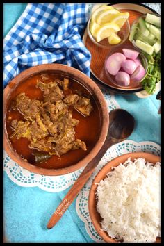 two bowls filled with food sitting on top of a blue table cloth next to other dishes