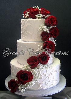 a wedding cake decorated with red roses and baby's breath