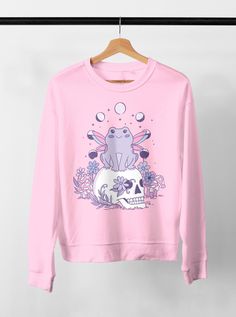 Harajuku Frog Pastel Goth Sweatshirt, Pastel Goth Clothing, Harajuku Shirt, Cryptid Shirt, Kawaii Clothes, Kawaii Goth, Creepy Cute Shirt DETAILS ♥ This pastel goth harajuku frog design is printed on a premium soft Bella+Canvas 3001 t-shirt, unisex jersey short sleeve tee ♥ 100% Airlume combed and ringspun cotton (fiber content may vary for different colors): solid colors are 100% cotton except Ash (99% cotton, 1% polyester), heather colors are 52% cotton, 48% polyester (Athletic Heather and Bla Kawaii Tops With Cartoon Print For Cosplay, Kawaii Cotton Tops For Cosplay, Cotton Kawaii Tops For Cosplay, Cute Crew Neck Tops For Cosplay, Clothes Kawaii, Goth Harajuku, Goth Kawaii, Pastel Goth Outfits, Harajuku Shirt