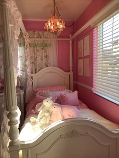 a white bed sitting under a window next to a chandelier